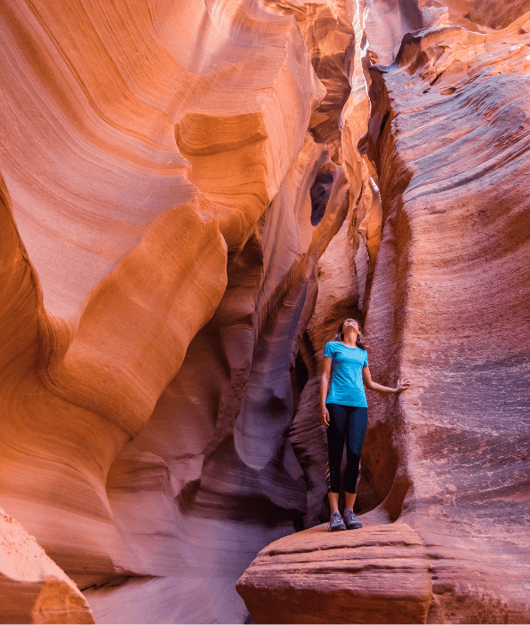 Hiker exploring narrow Antelope-style slot canyon with dramatic sandstone walls