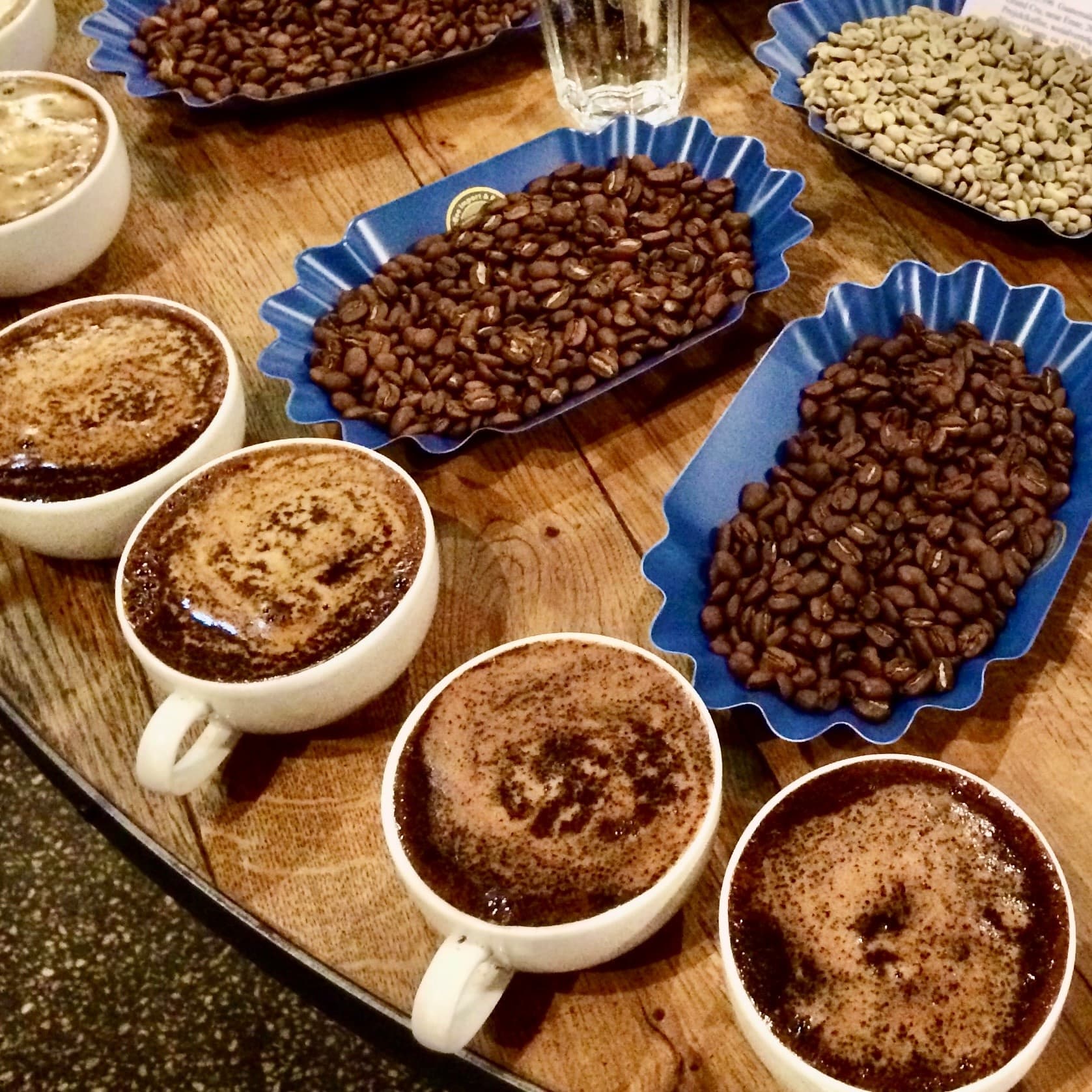 Coffee cupping setup with brewed cups and green beans at Kaffeemuseum Burg