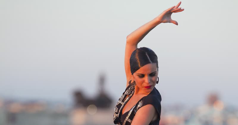 Close-up flamenco dancer performing outdoors with blurred city