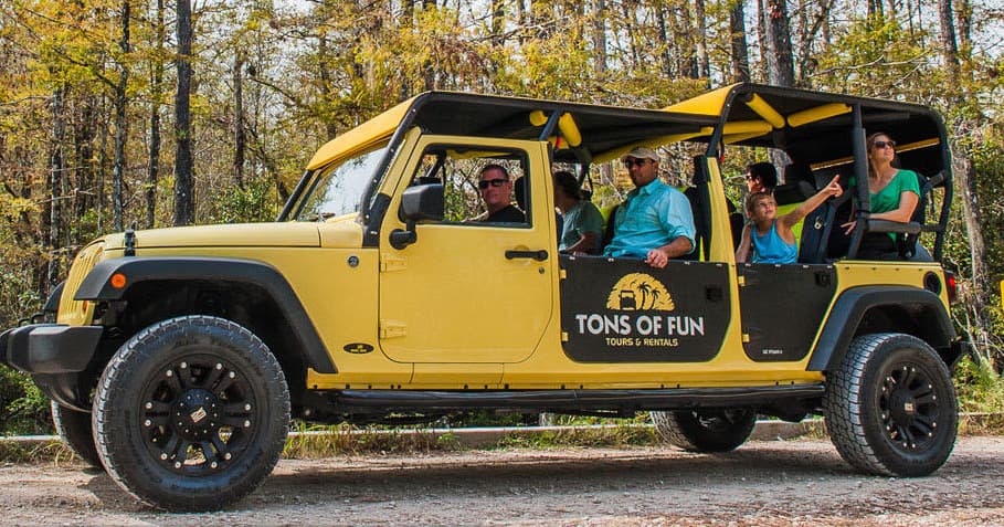 Open-air Jeep tour with smiling passengers in wooded trail