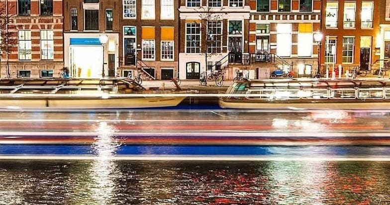 Light-trail boat streaks on Amsterdam canal at dusk