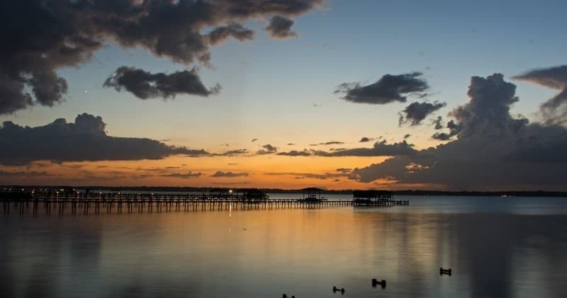 Sunset over calm bay with pier, panoramic coastal vista