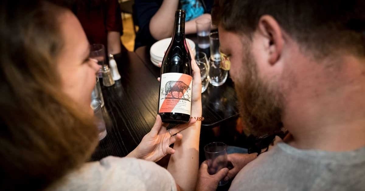 Couple examining wine bottle during indoor tasting at bar