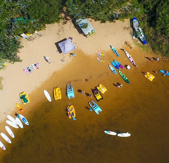 Aerial beach shot with kayaks and rental paddlecraft on sand