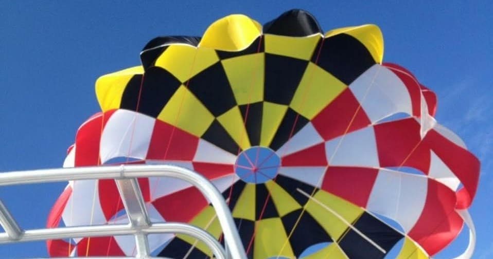 Colorful parasail canopy inflating above boat deck on sunny day