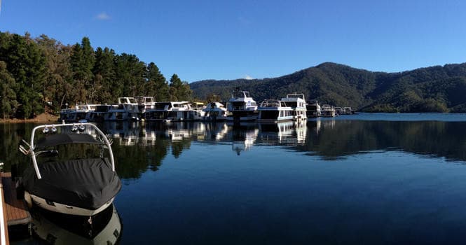 Boats moored at tranquil lake marina with mountain reflections
