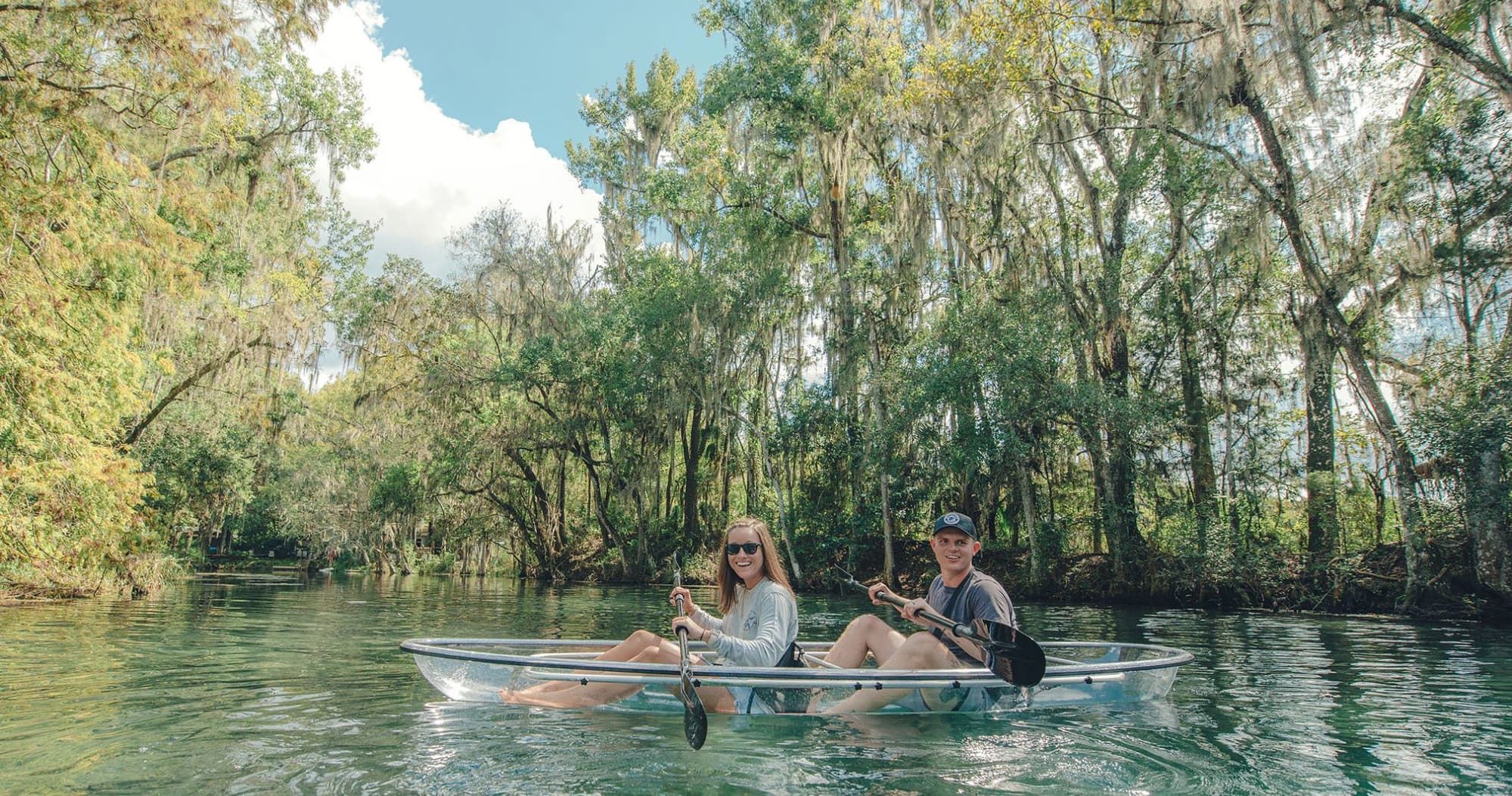 Couple kayaking in a clear river through shaded mangrove springs