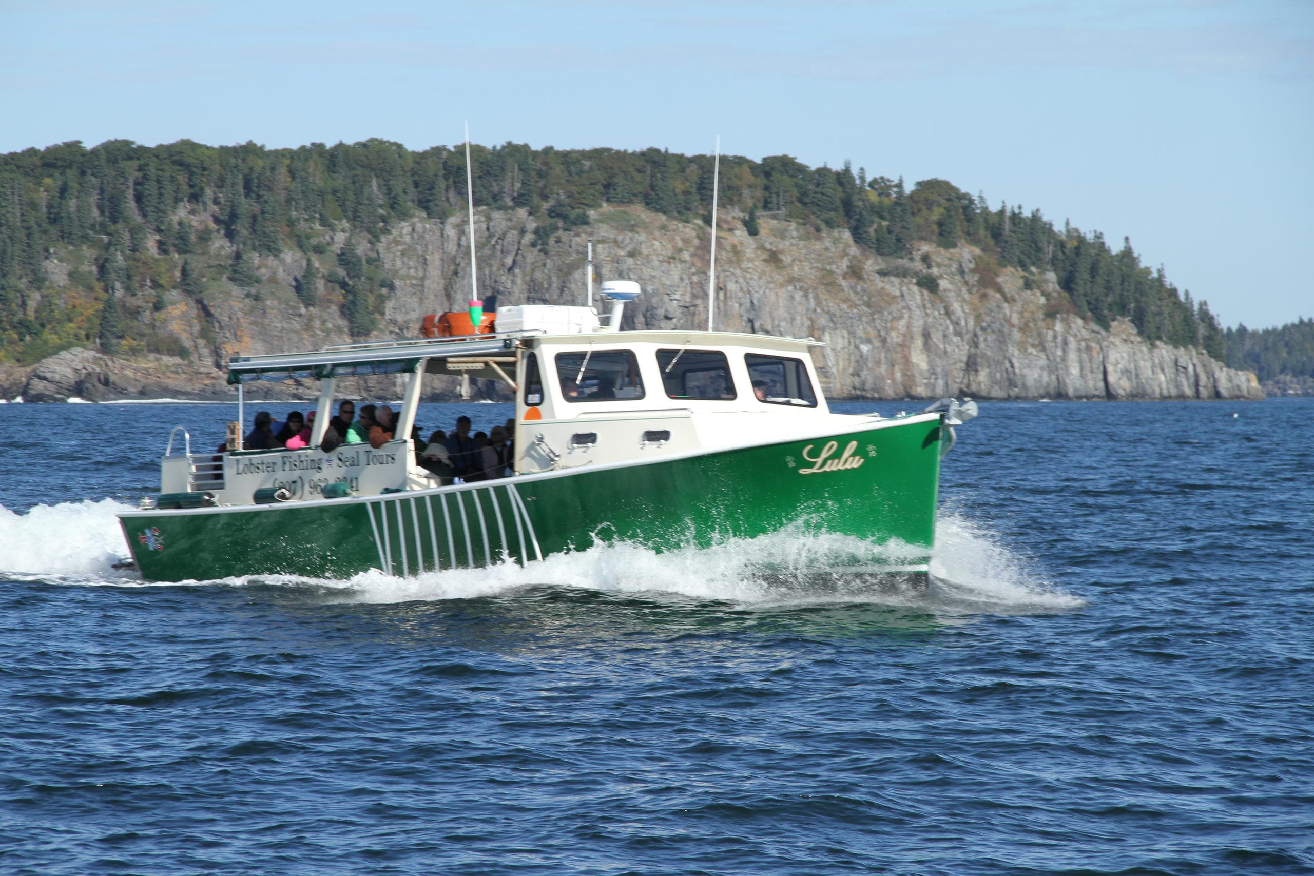 Spectator boat cruising scenic rocky shoreline with passengers