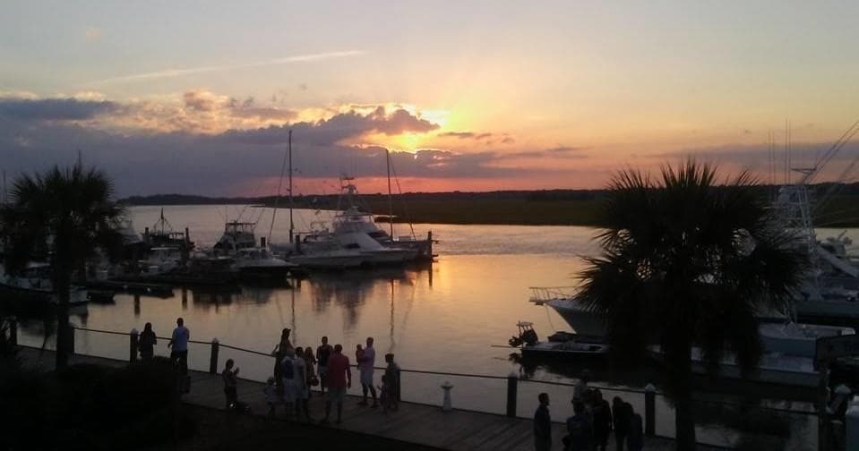 Sunset marina with sailboats and waterfront crowd in Charleston