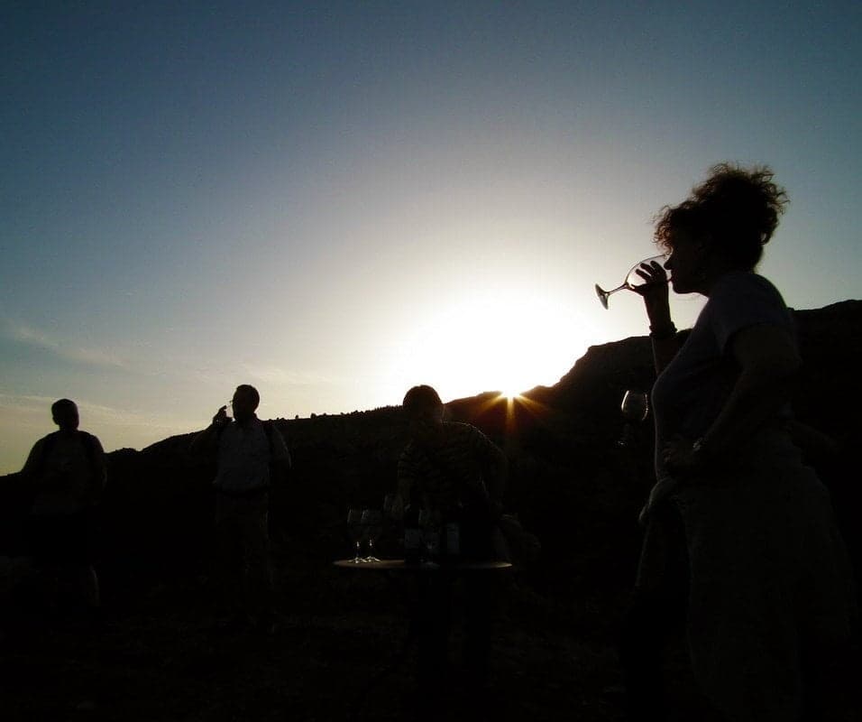 Silhouetted group enjoying sunset drinks on ridgeline hike