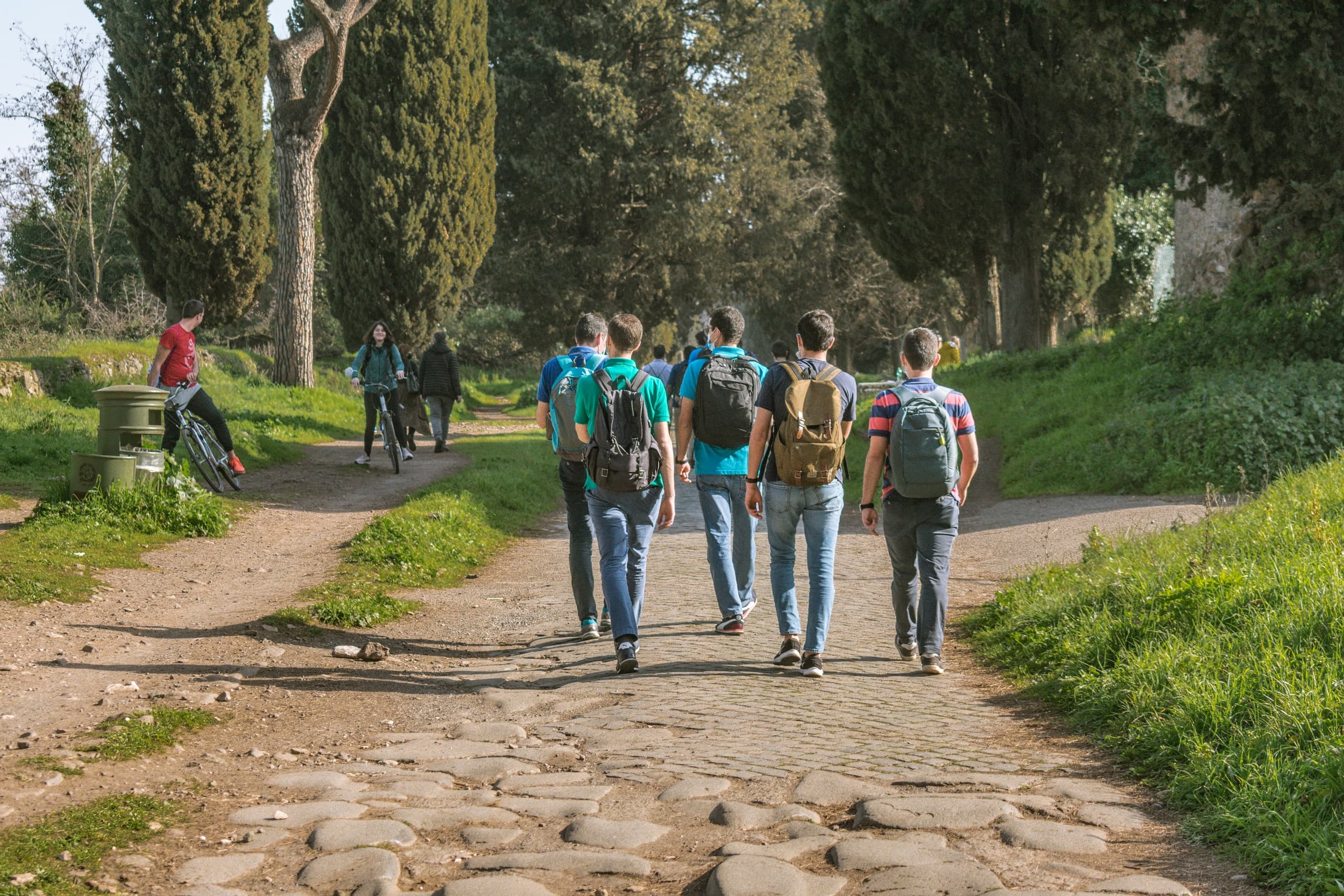 Group hiking along ancient paved road through green countryside