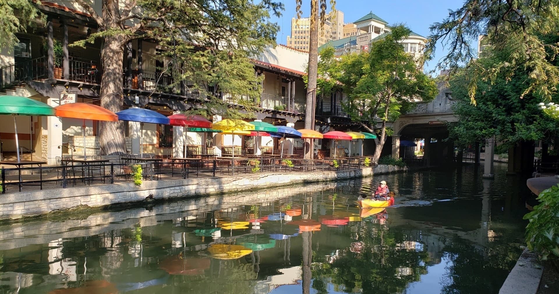 Kayakers paddling along San Antonio River Walk with riverside cafes