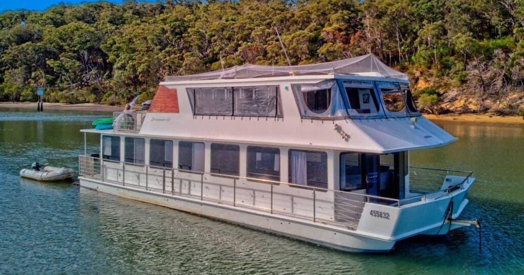 Luxury houseboat cruising calm river with forested shore