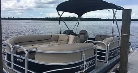 Docked pontoon boat at marina showing seating and canopy