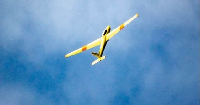 Yellow glider soaring against blue sky during scenic flight