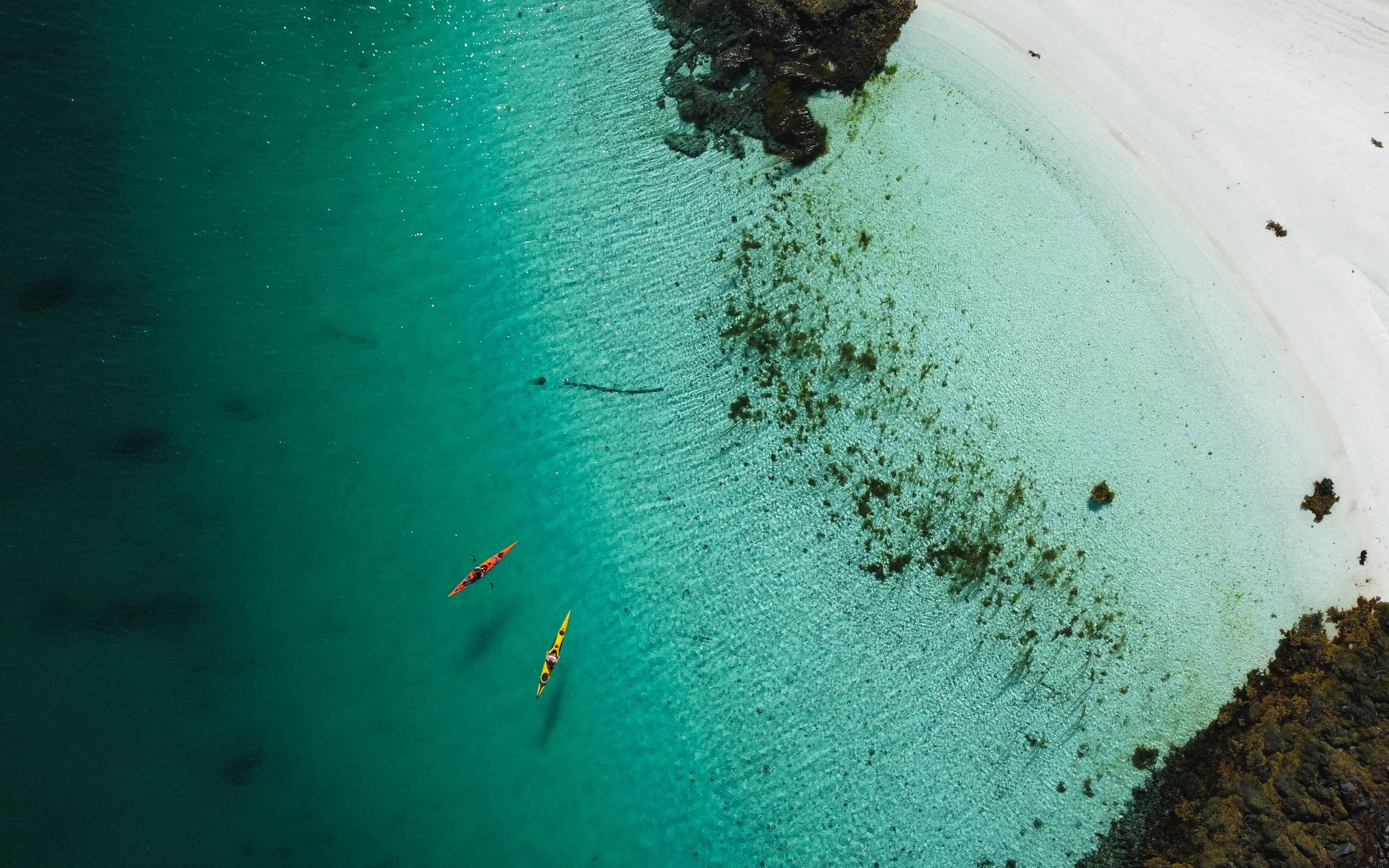 Aerial view of two kayaks in turquoise shallow Arctic bay