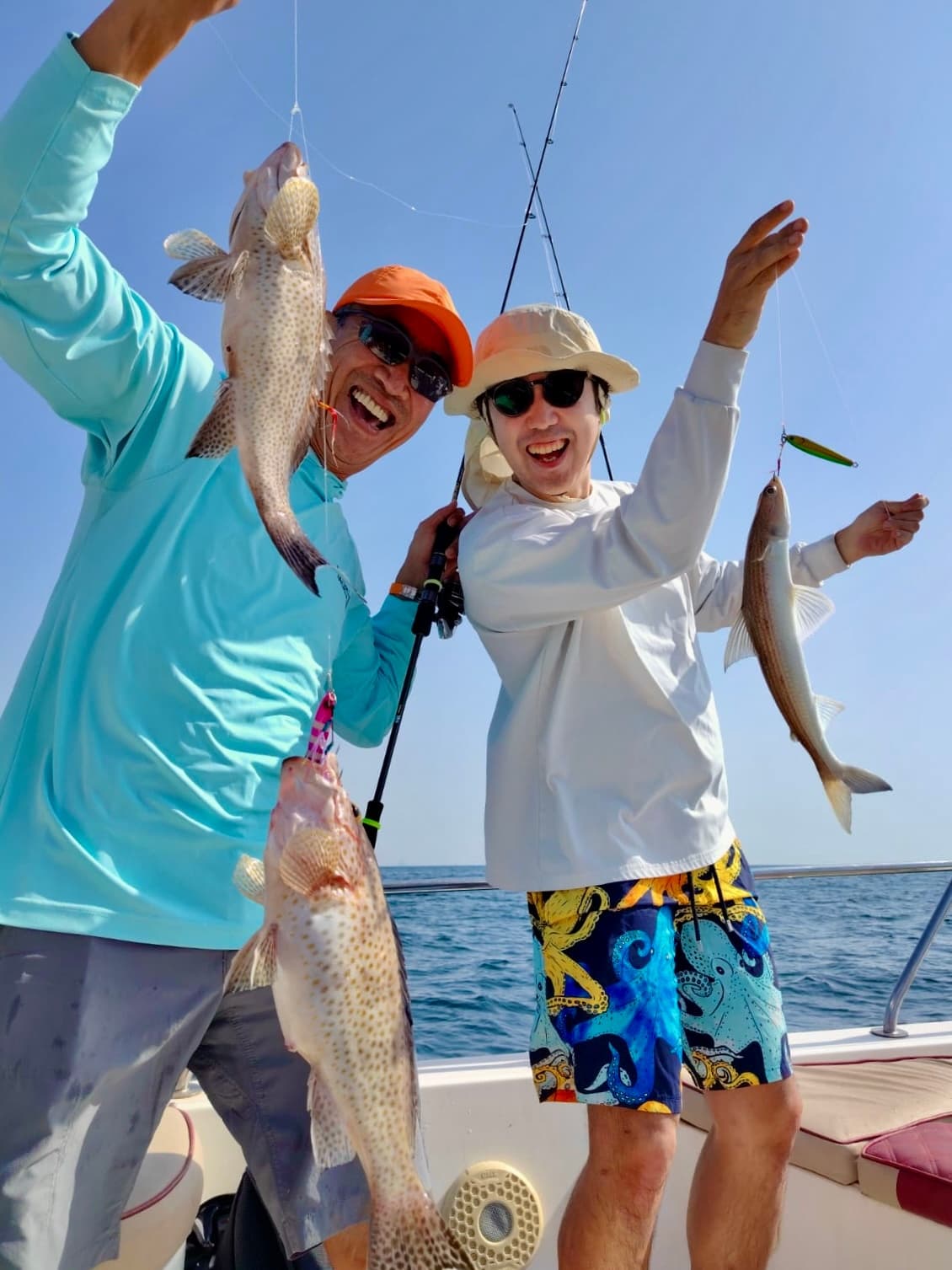 Two anglers celebrating with fish catch aboard sportfishing boat at sea