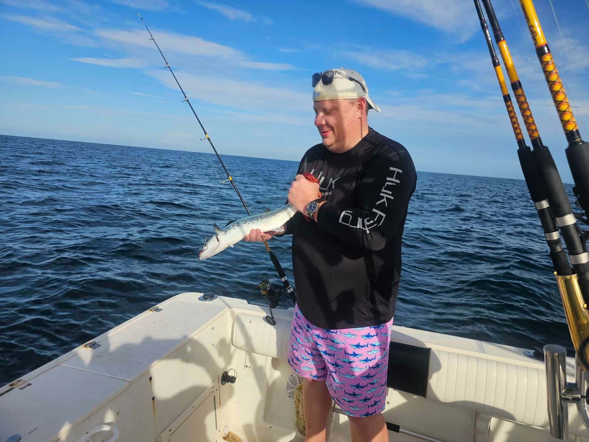 Angler holding caught fish on offshore charter boat in open ocean
