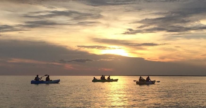 Kayakers silhouetted at sunset paddling Gulf waters near St. George Island