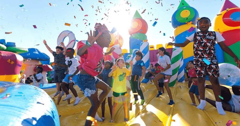 Children dancing with confetti on giant outdoor inflatable at fair