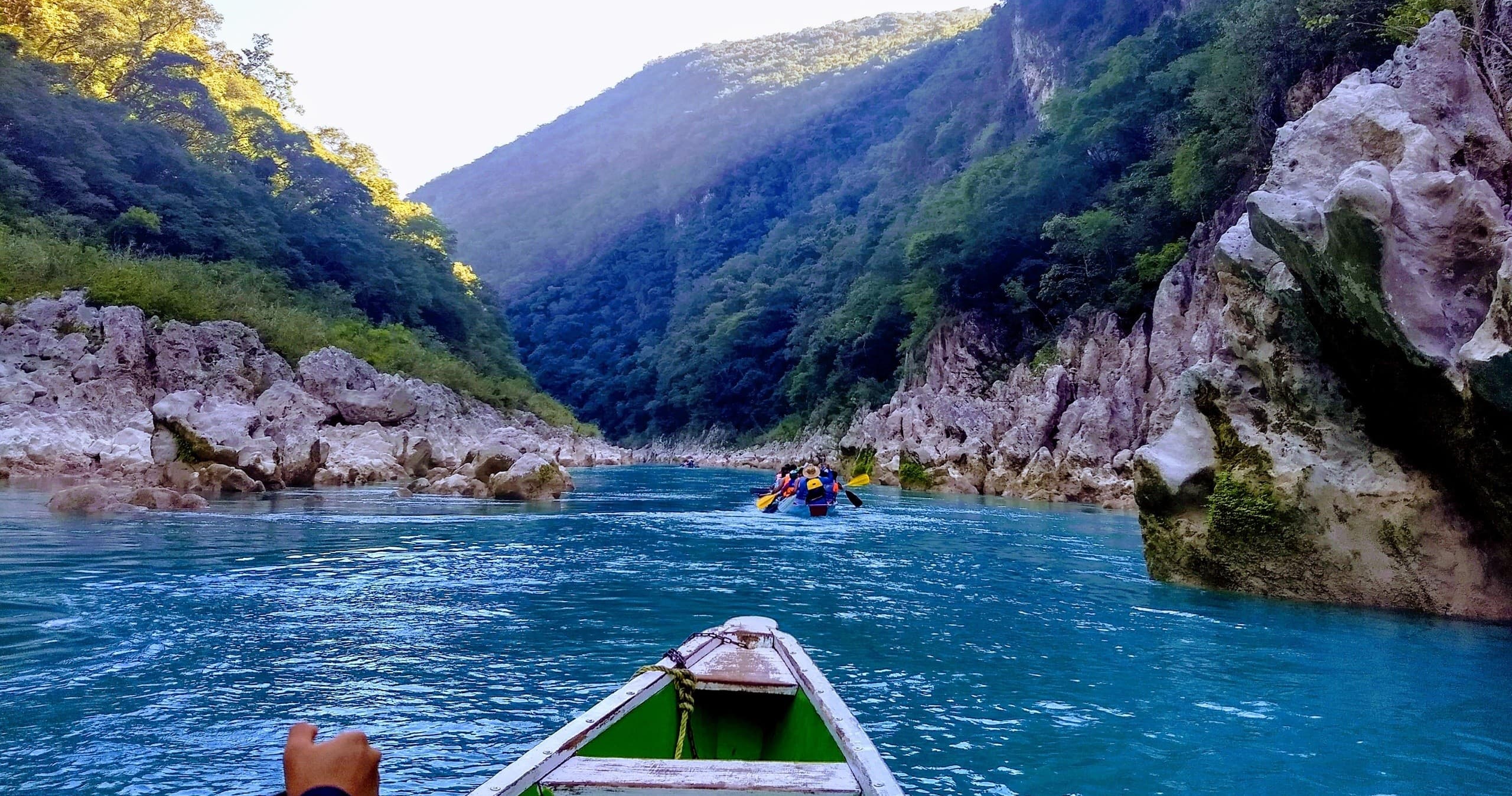 Paddlers in a small boat on emerald canyon river excursion