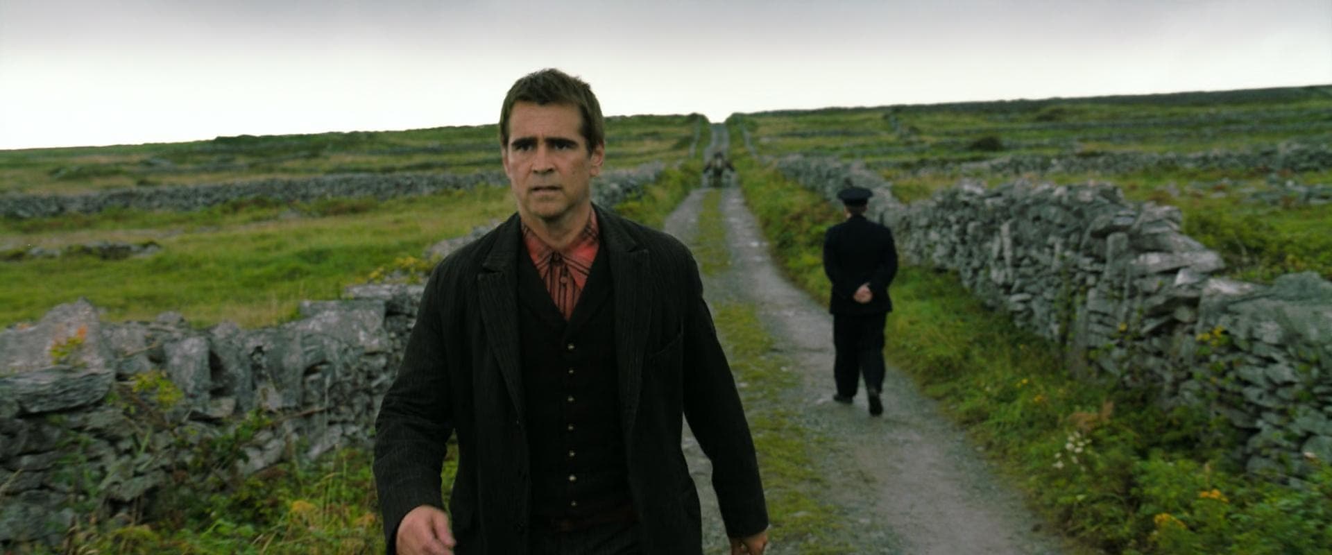 Man walking rural stone lane on grassy Aran Islands coastal landscape