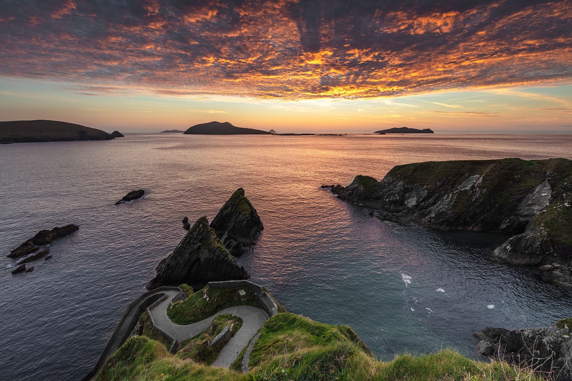 Dramatic sunset over coastal cliffs with winding headland road