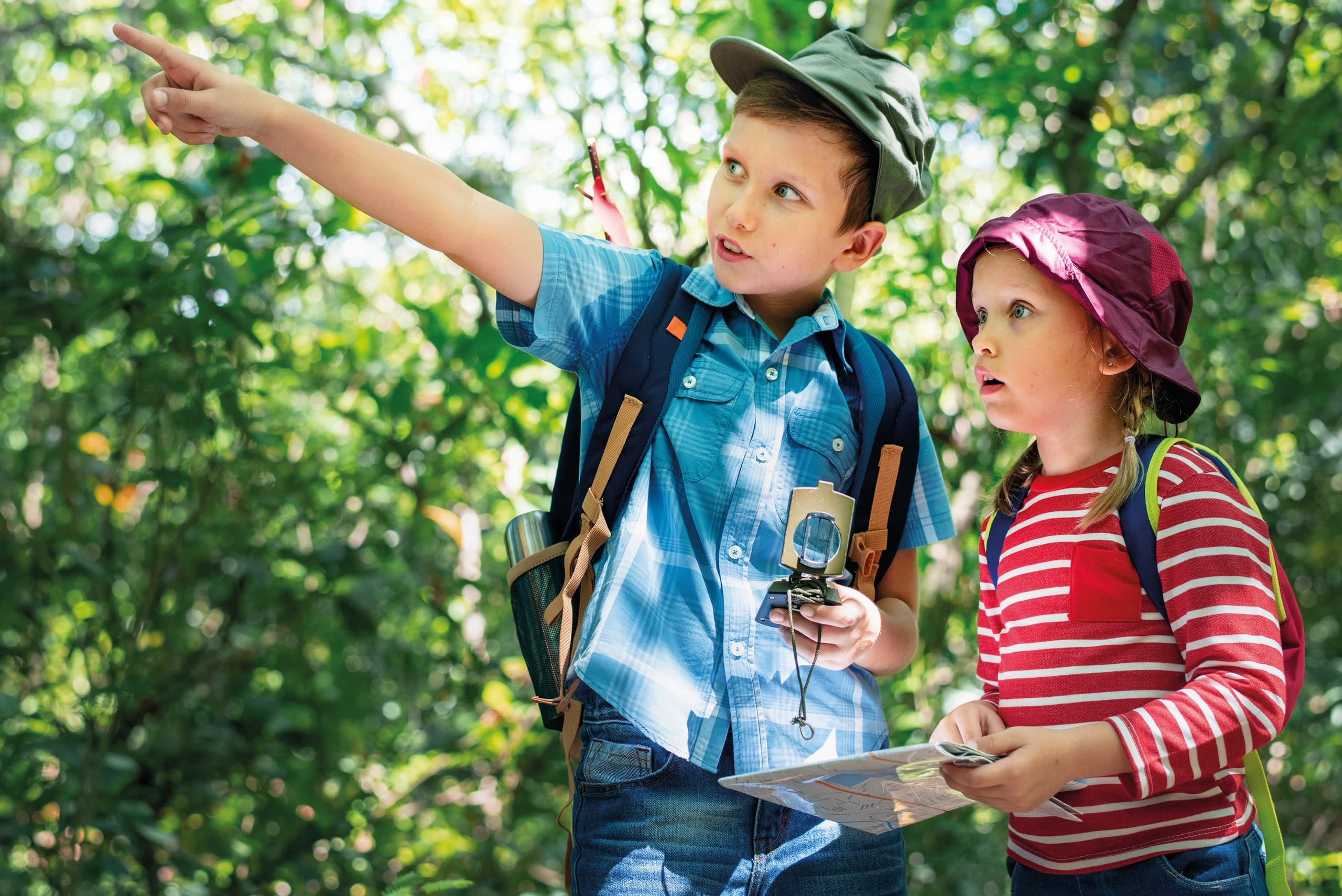 Children exploring forest with map and compass on hiking trip