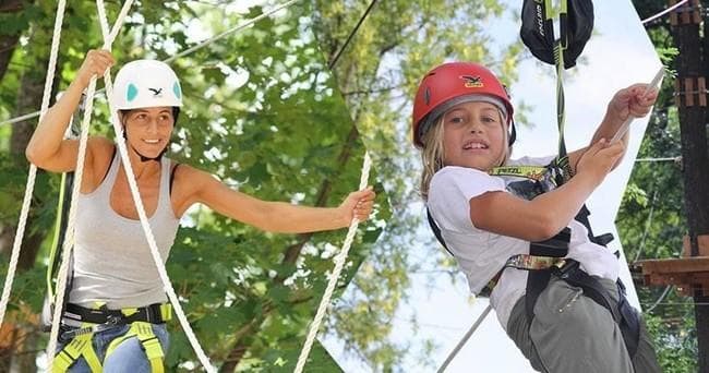 Children on high ropes and zipline in forest adventure park