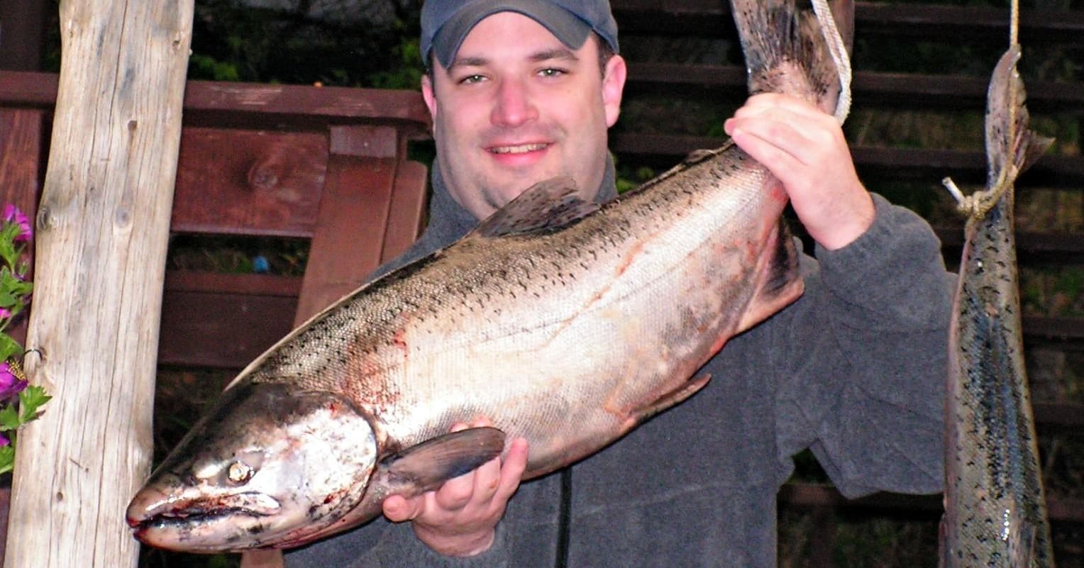 Angler holding large salmon catch at docked waterside