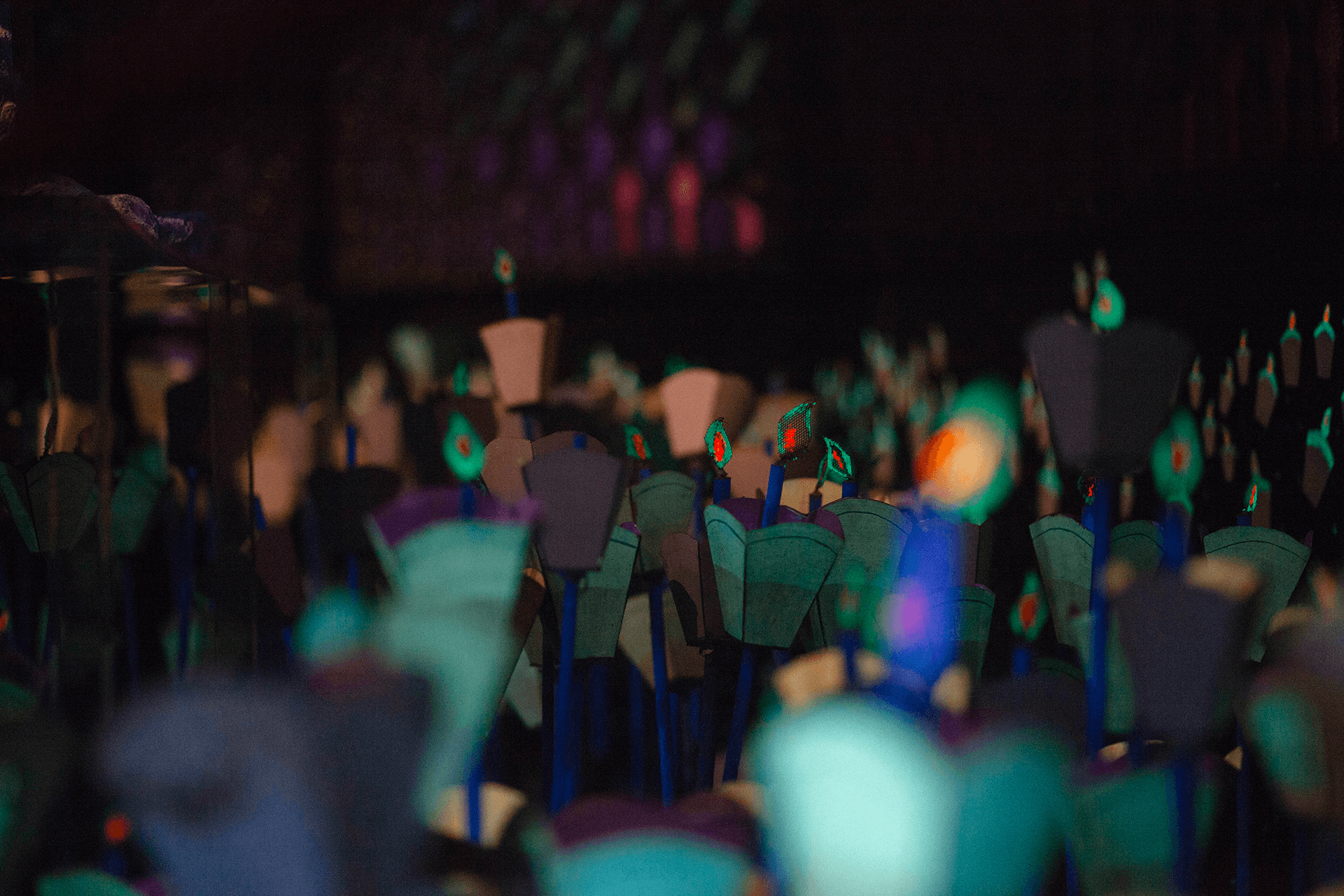 Blurred candlelit figures in dim indoor exhibit, atmospheric lights