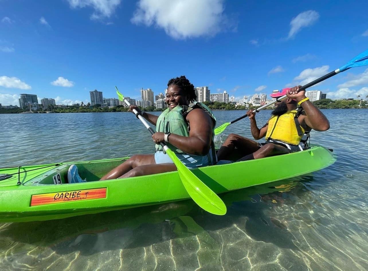 Two kayakers paddling clear shallow tropical water near shore