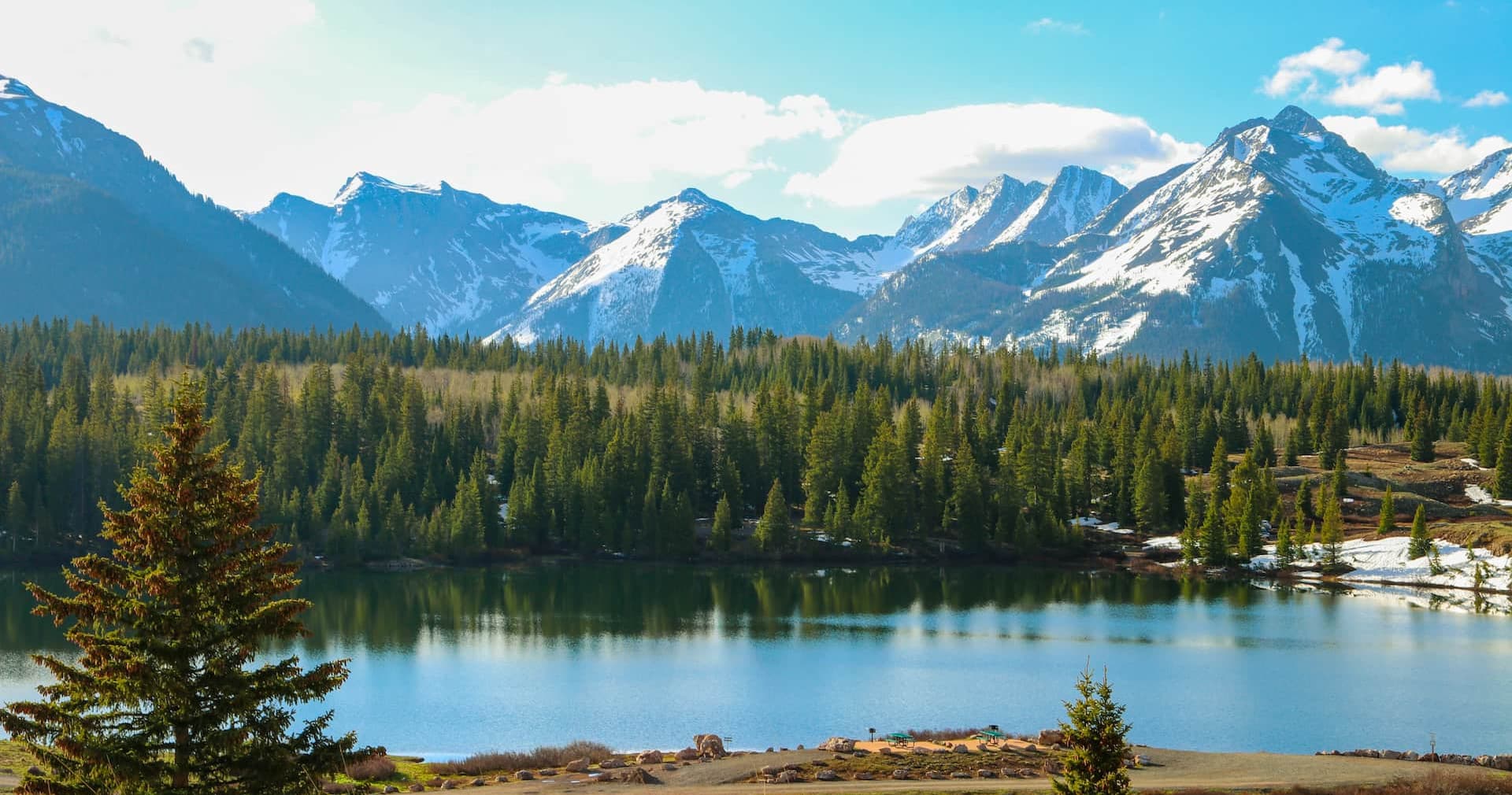 Scenic mountain lake vista with pine forest and snowy peaks