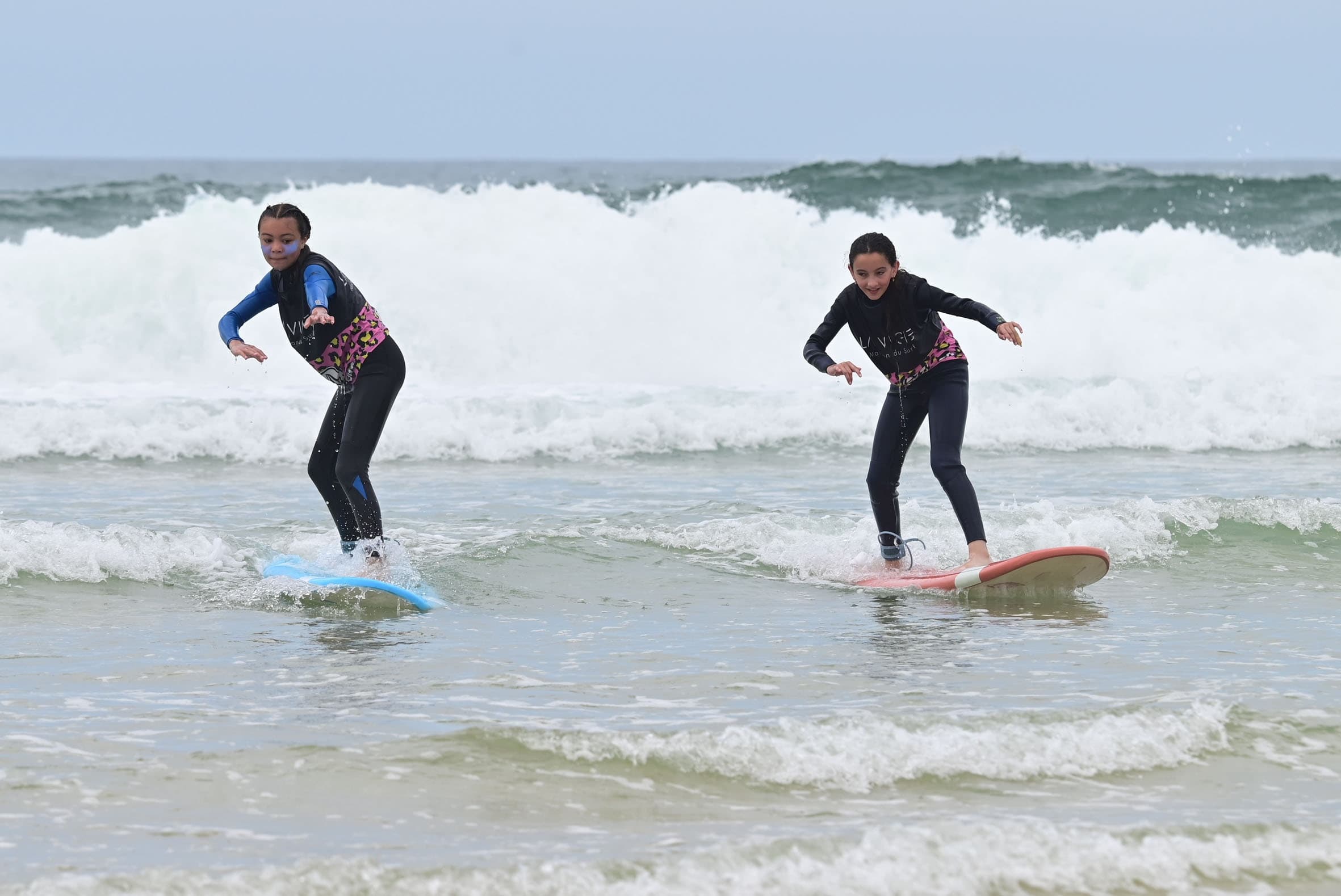 Two surfers riding shorebreak waves during lesson at Biscarrosse