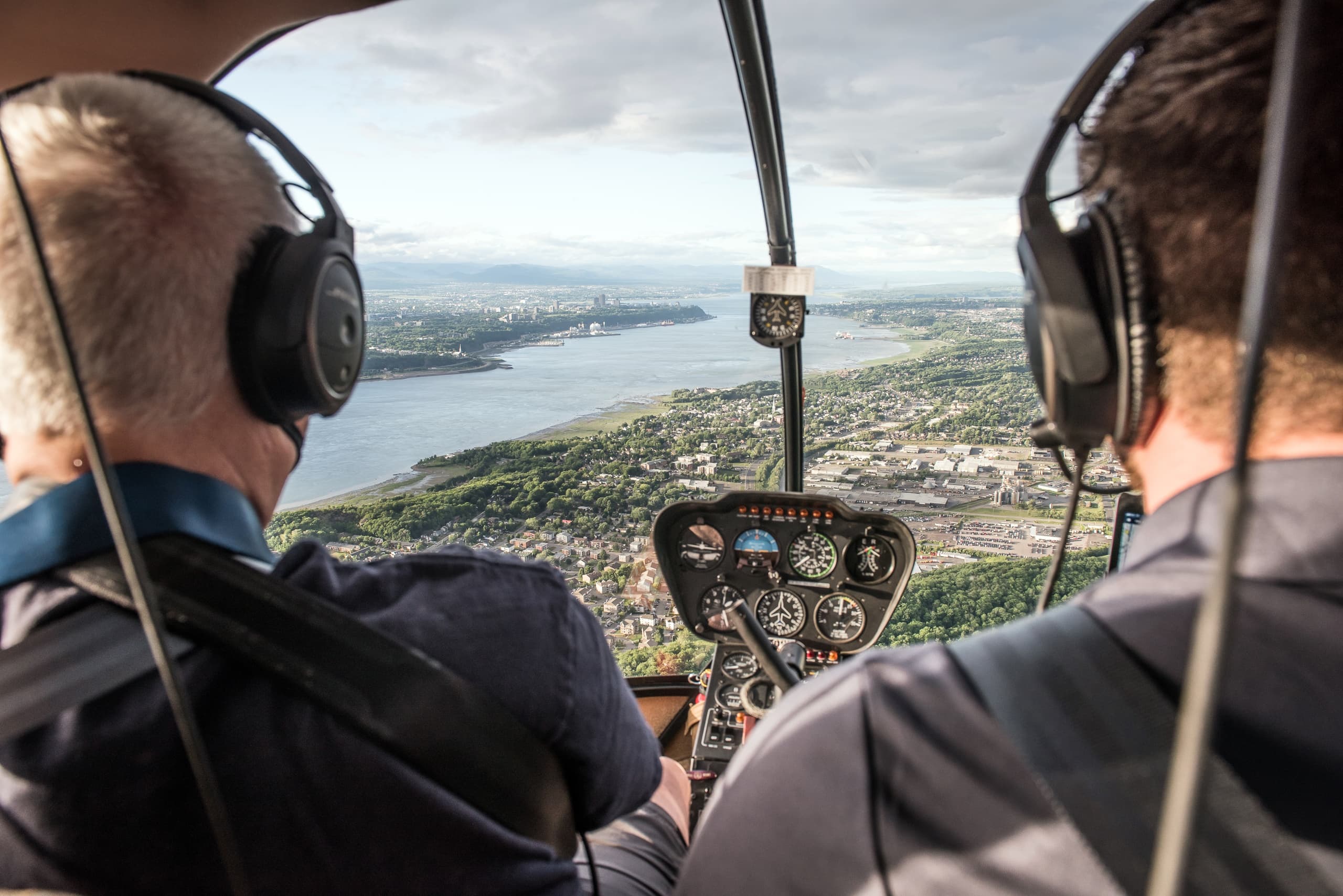Backseat view of helicopter pilots flying over city landscape