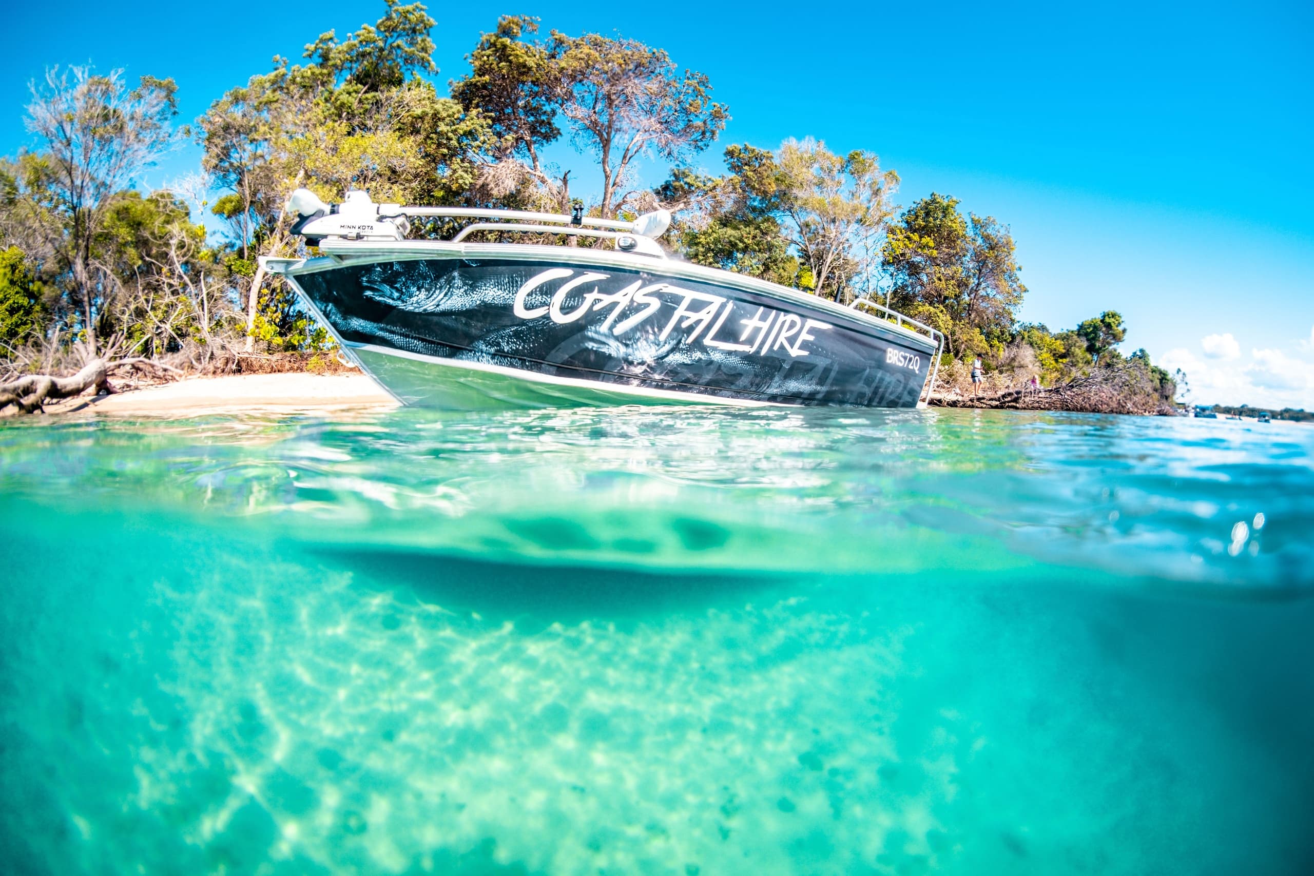 Boat anchored in turquoise coastal shallows, snorkeling-ready