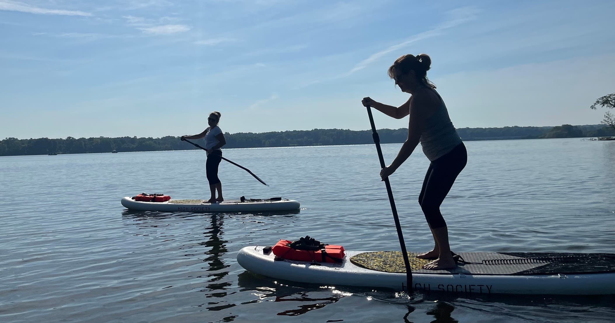 Standup paddleboarding near shore with two participants on calm lake