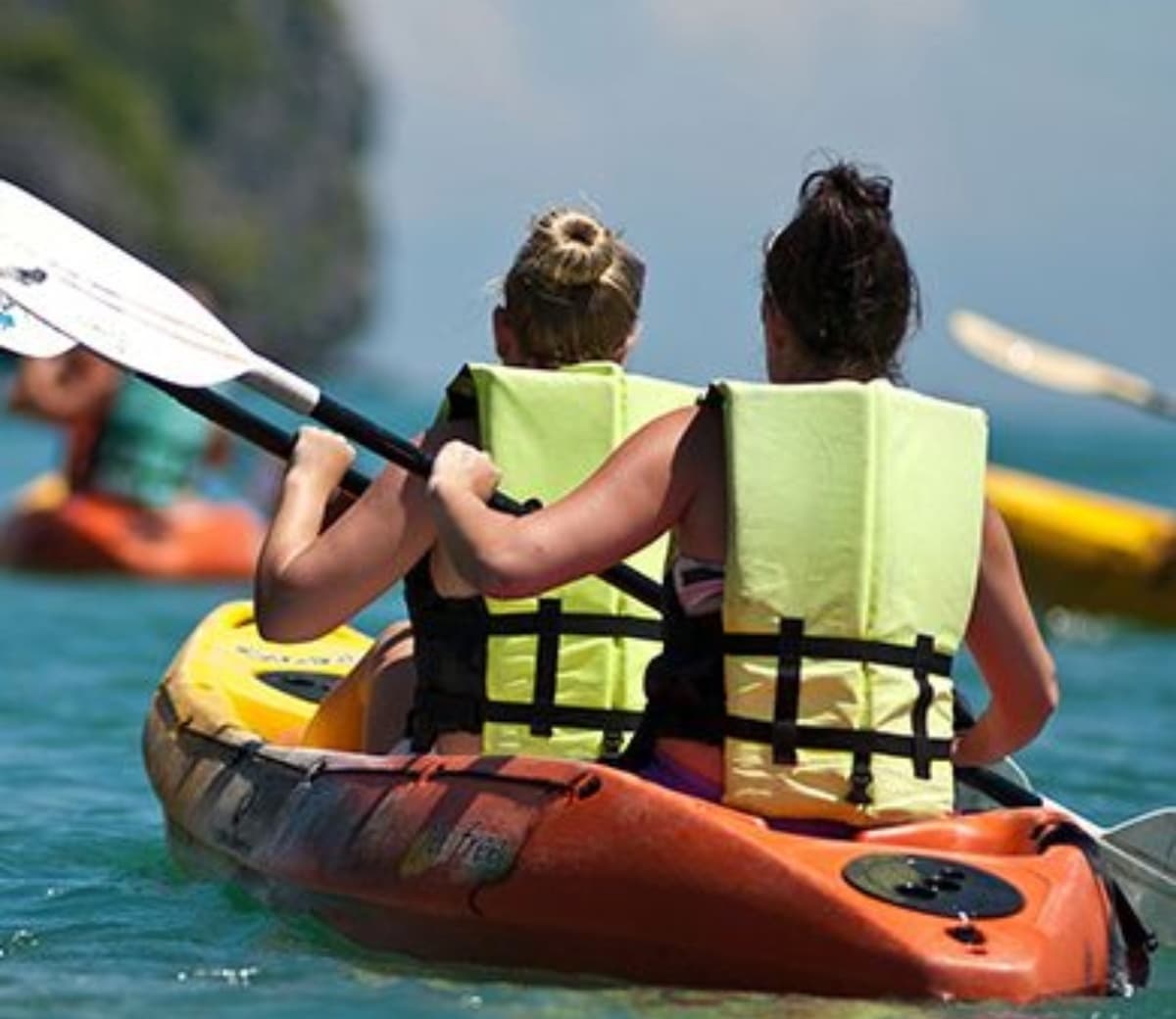 Two kayakers tandem paddling in clear turquoise coastal waters