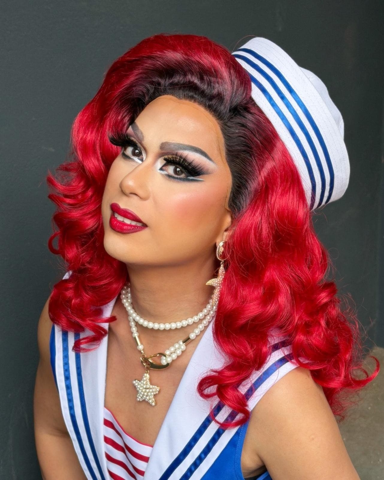 Drag queen in sailor costume portrait with vibrant red hair