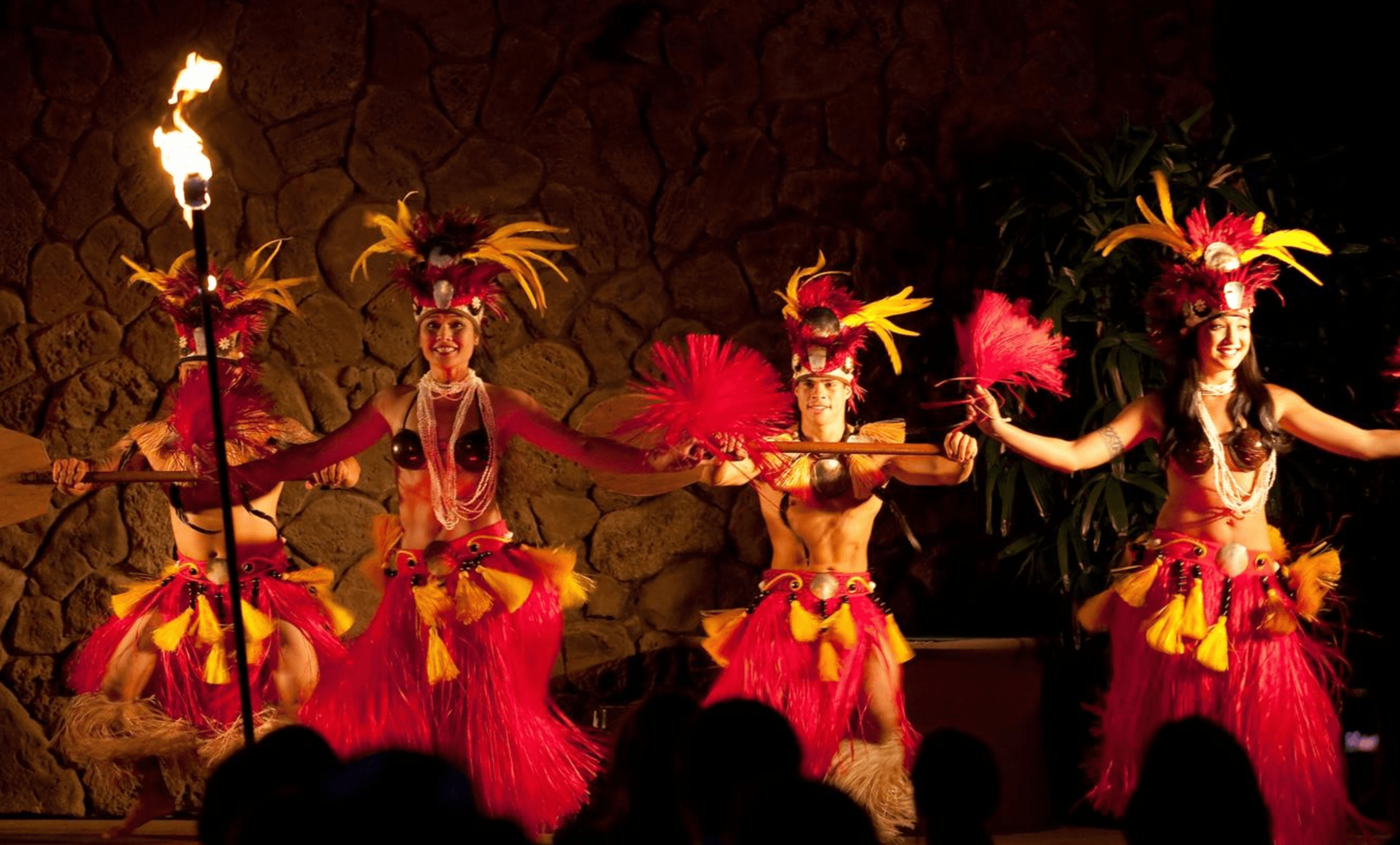 Tahiti-style dancers performing with torches on luau stage