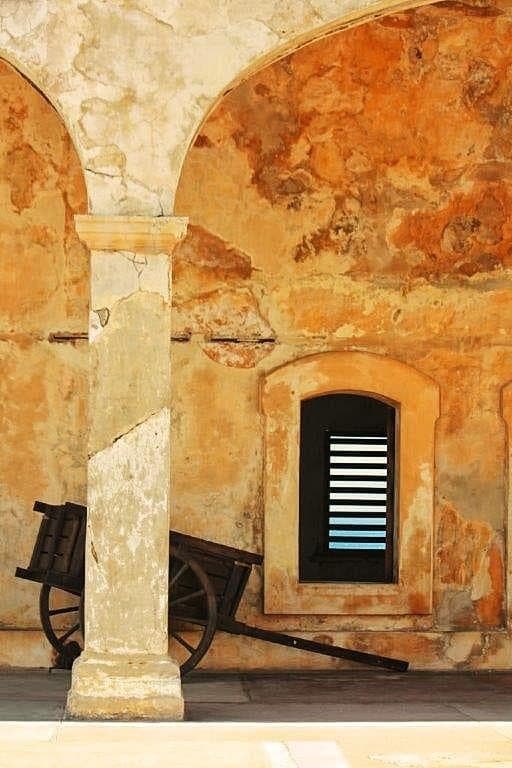 Historic arched courtyard with cart and shuttered window in Old San Juan