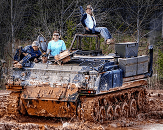Armored vehicle mud run with riders on tracked APC