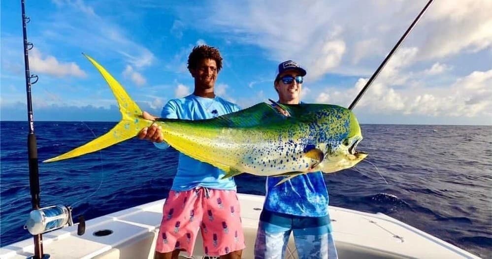 Anglers holding large mahi-mahi on offshore sportfishing boat