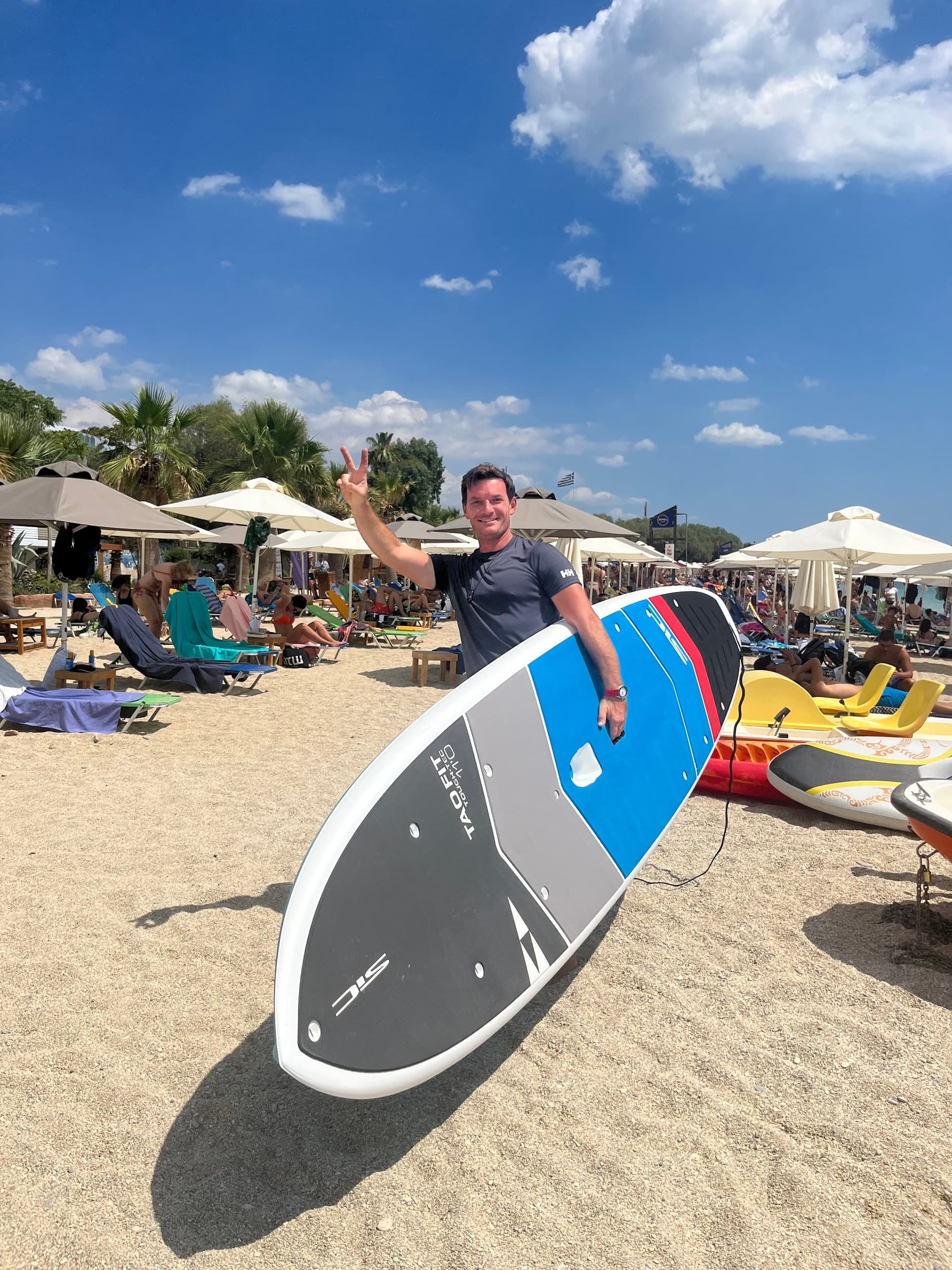 Stand-up paddleboarder carrying board on sunny sandy beach
