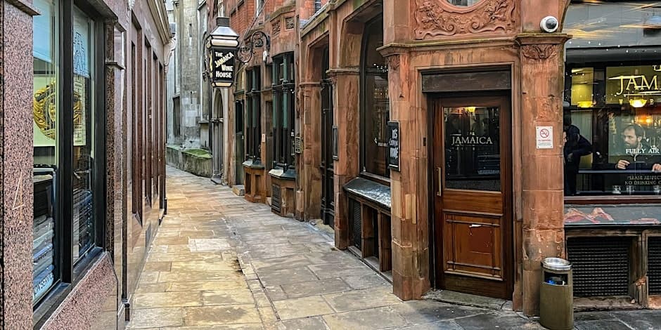 Narrow cobbled alley with historic pubs for walking tours
