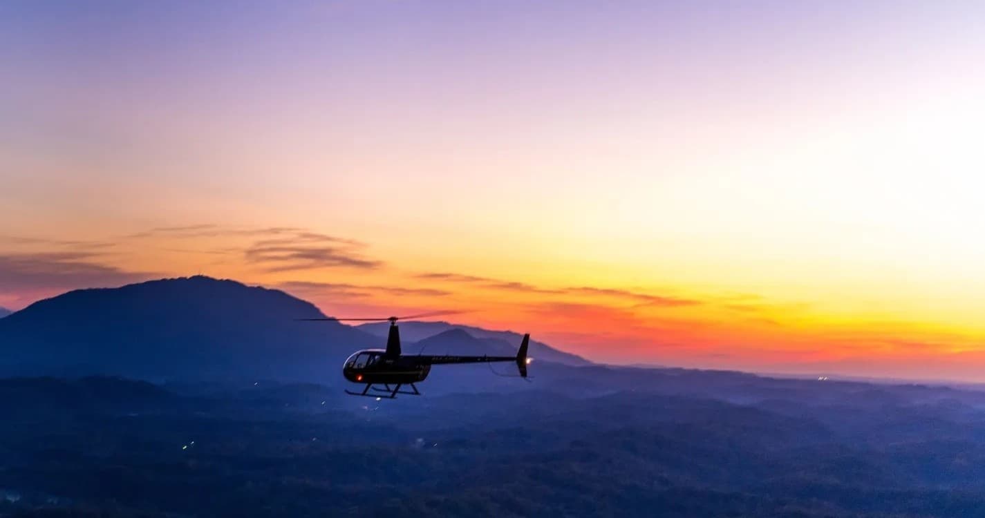 Helicopter silhouette flying over mountain sunset vista