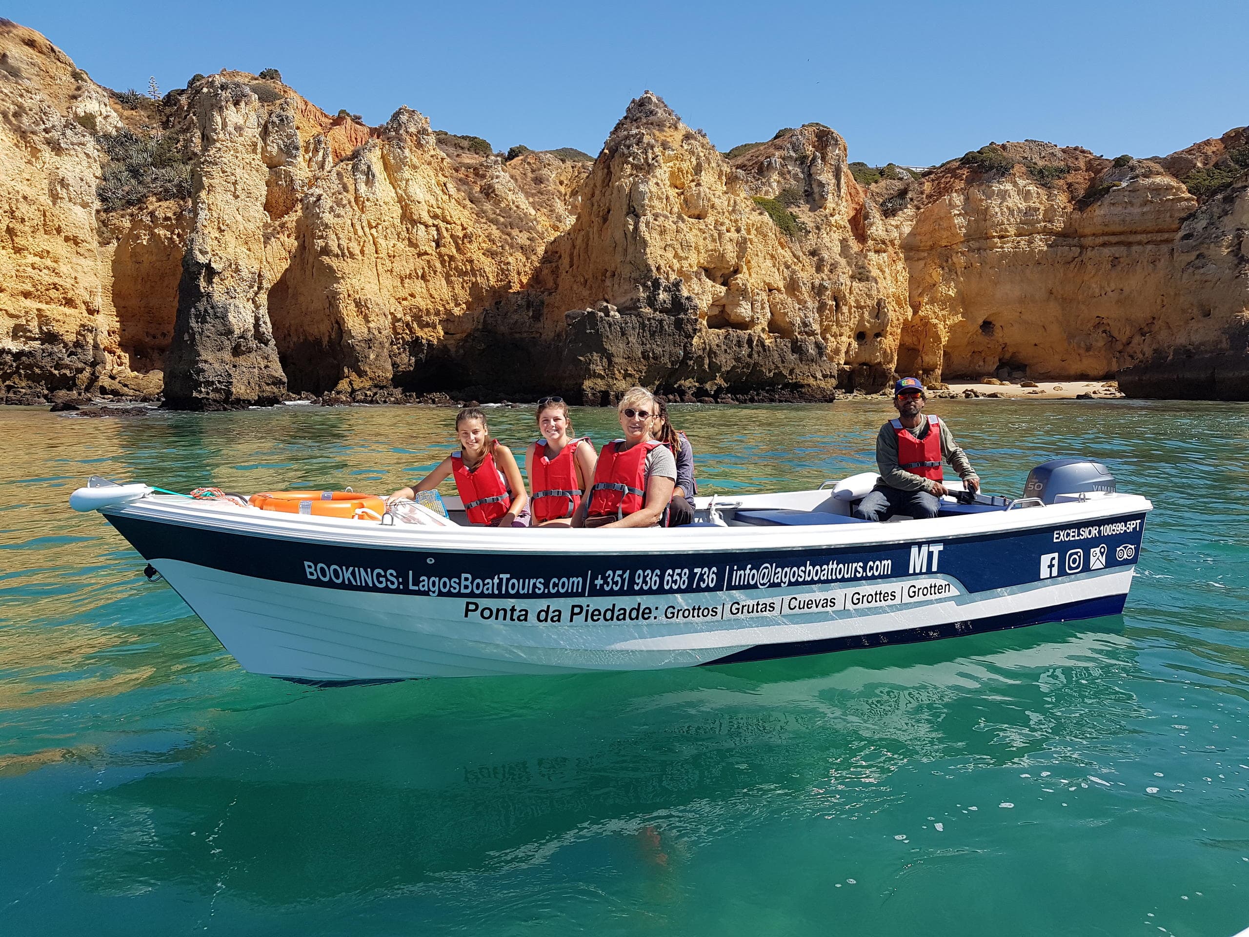 Kayakers paddling through clear blue lagoon near rocky cliffs