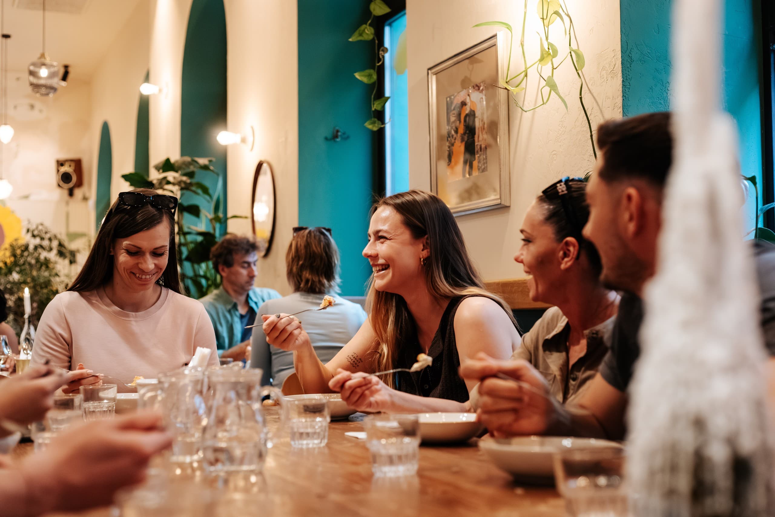 Friends enjoying communal dinner at a cozy Budapest indoor restaurant