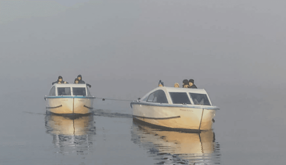 Two motorboats moored in mist on Loch Goil with reflections