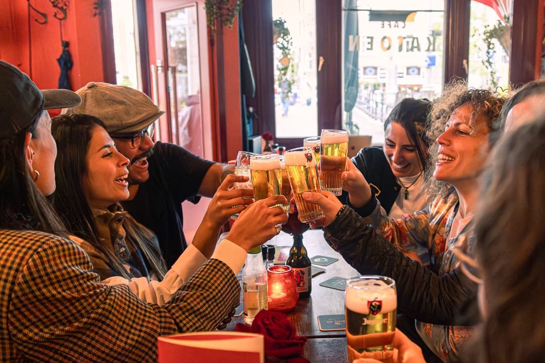 Group toasting beers inside cozy pub during food tasting tour
